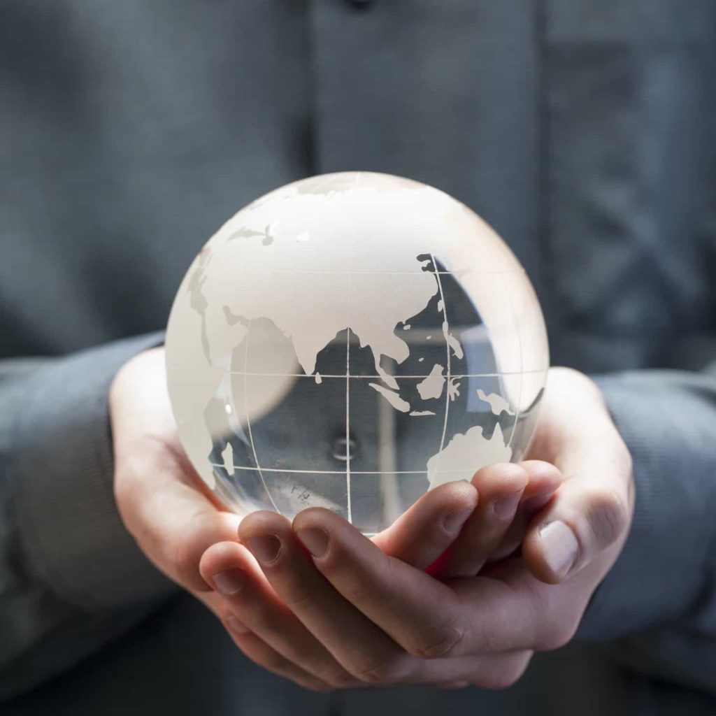 Hands holding a glass globe of the world.